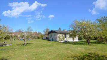 Et hus med have, gyngestativ og et picnicbord.
