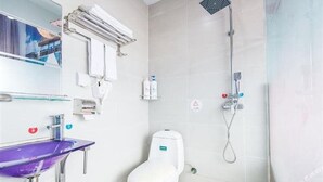 Un baño con inodoro blanco, lavamanos morado y ducha.
