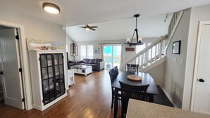 A spacious living area with hardwood floors, a dining table, and a staircase leading to an upper level. - Jamaica Beach! Fishing light, kayaks, pool access! (Jamaica Beach)