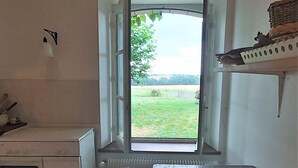 A kitchen with a large window, a wooden table, and a radiator.
