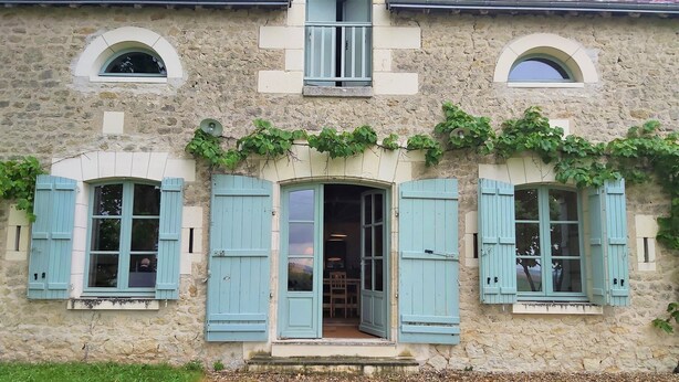 A stone building with arched windows and blue shutters.