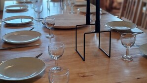 A long wooden dining table set with plates, wine glasses, and cutlery.
