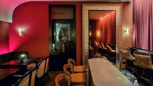 A bar area with a curved counter, wooden chairs, and a mirror with a decorative frame. - Liu Men Melaka (Malacca City)