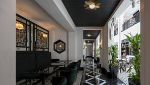 Un interior moderno con suelo de baldosas blanco y negro, una zona de estar con mesas y sillas, y una lámpara decorativa en el techo.