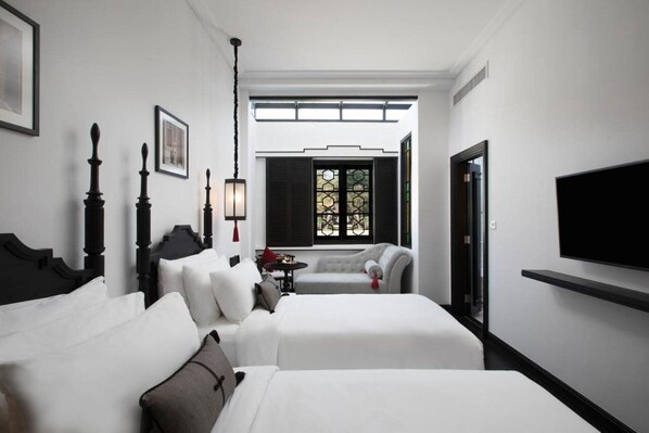 Relax in a spacious room with a large bed, a smaller bed, a tufted sofa, and a flat-screen TV.
