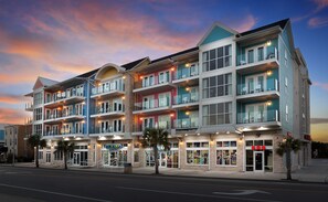 Un hôtel à plusieurs étages doté de balcons, d’une façade sur le thème de la plage et d’une devanture avec une enseigne indiquant « OCÉAN ».