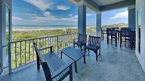 A covered outdoor area with a view of the beach, featuring a table and chairs.
