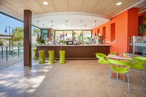 Un espace bar moderne comprenant un comptoir, des tabourets de bar et un coin salon avec des chaises.