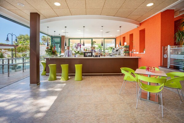 Un área de bar moderna con mostrador, taburetes y un espacio de estar con sillas.