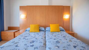 Una cama doble con ropa de cama floral, dos mesitas de noche con lámparas, un cabecero de madera y un aparador pequeño de madera.