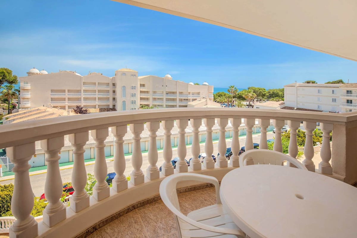 Un balcon offrant une vue sur un complexe hôtelier, une piscine et un ciel dégagé.