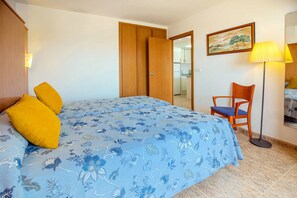 Une chambre à coucher avec un lit, une chaise, une lampe et un tableau au mur.