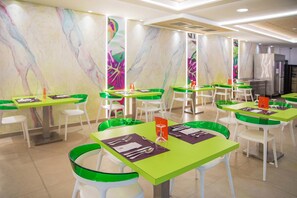 Un restaurant avec des tables et des chaises vertes et blanches, des décorations murales en marbre et un aménagement intérieur moderne.