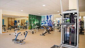 Une salle de sport équipée de divers appareils d’exercice, de miroirs et dotée d’un sol carrelé.