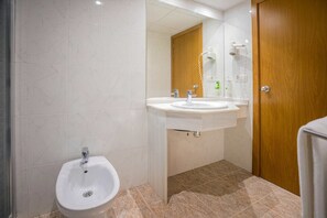Une salle de bain équipée d’un bidet, de deux lavabos, d’un miroir et d’une porte en bois.