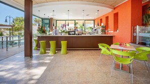 Een moderne bar met een toonbank, barstoelen en een zithoek met stoelen.