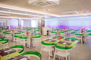 Un vaste espace de restauration intérieur, doté de nombreuses tables et chaises disposées en rangées.