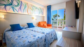 Habitación de hotel con dos camas, un escritorio, una silla, un televisor y un balcón con vistas.