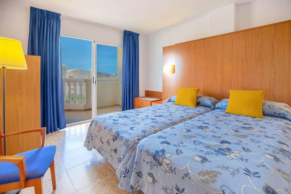 Une chambre d’hôtel avec un lit, une chaise, une table de chevet et une vue sur l’extérieur.