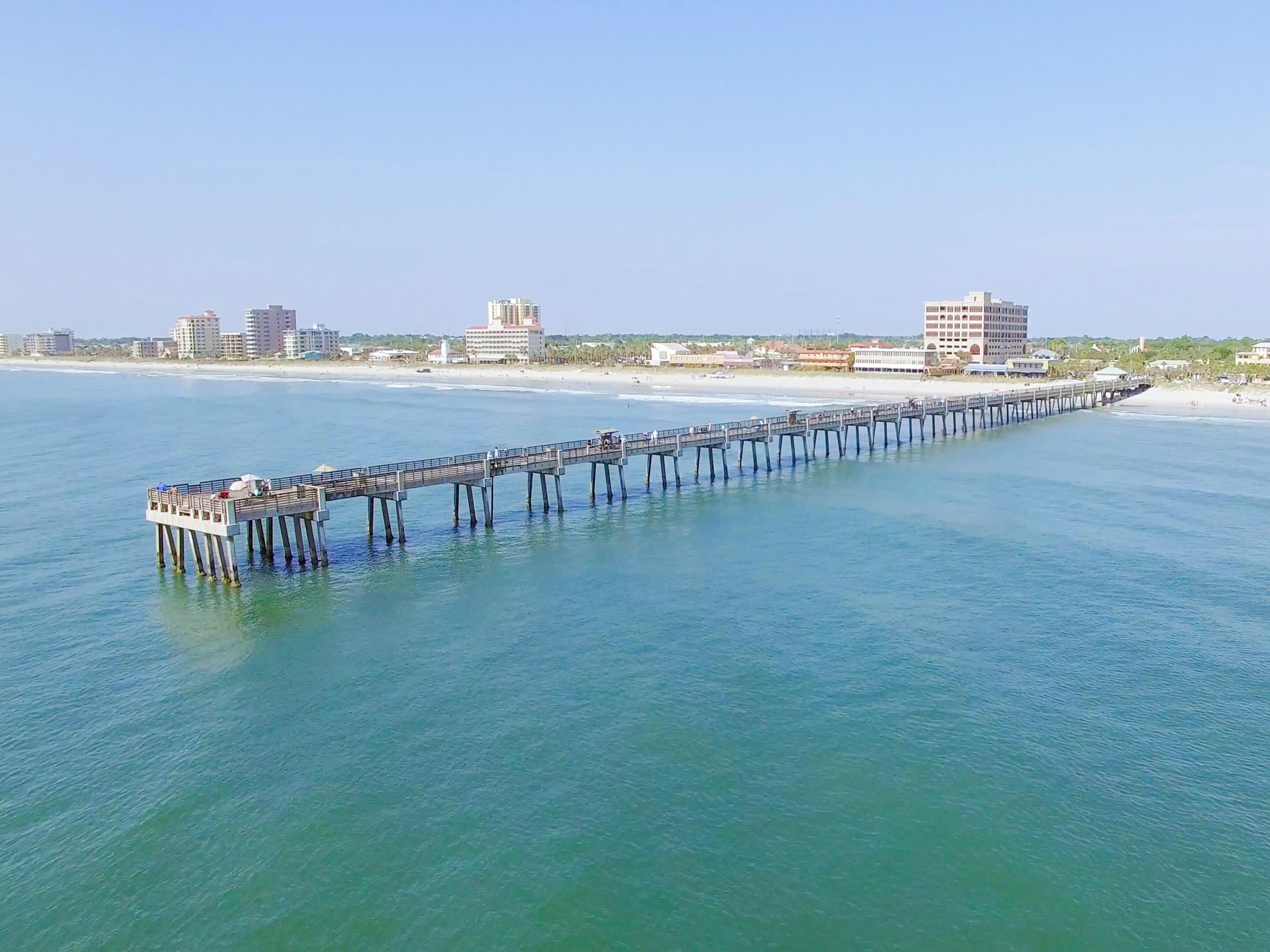 Un muelle largo que se adentra en el océano, con edificios al fondo.