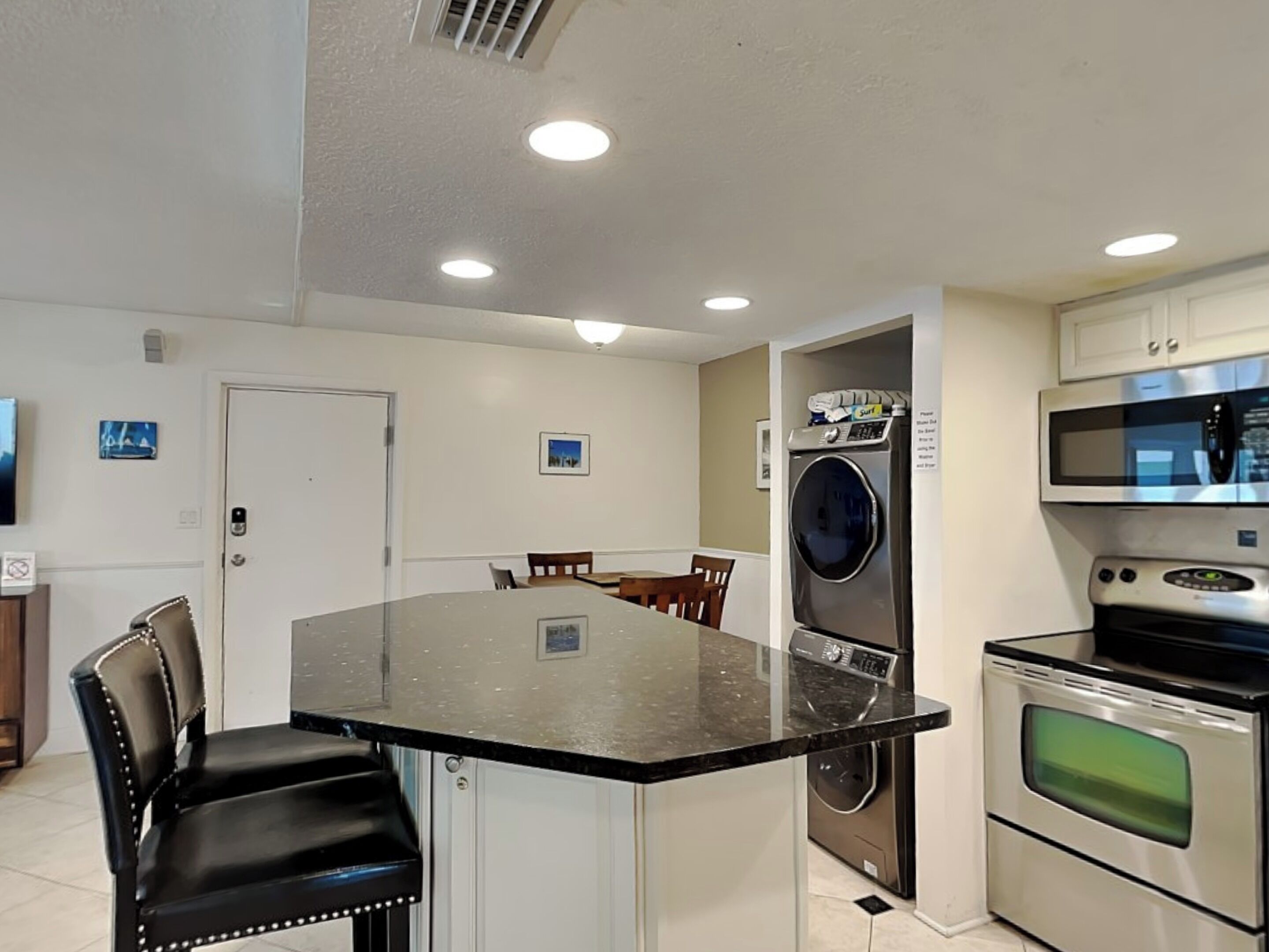 Una cocina compacta con una isla central, microondas, horno y lavadora.