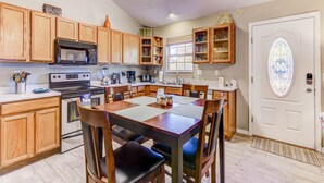 A kitchen with wooden cabinets, a stove, and a dining table with chairs.