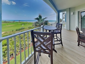 Varanda com vista para um campo de golfe e o oceano.