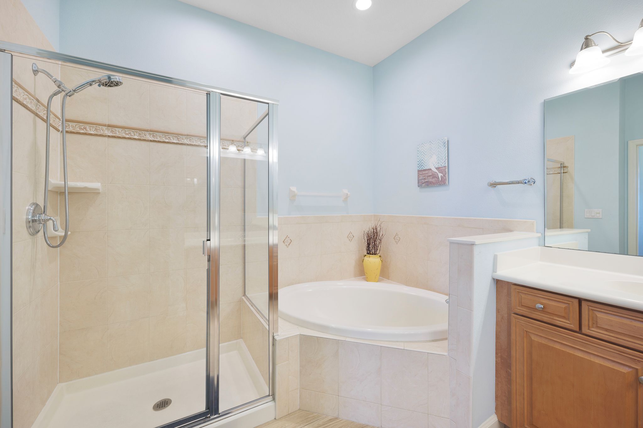 A bathroom with a glass-enclosed shower, a bathtub, and wooden cabinets.