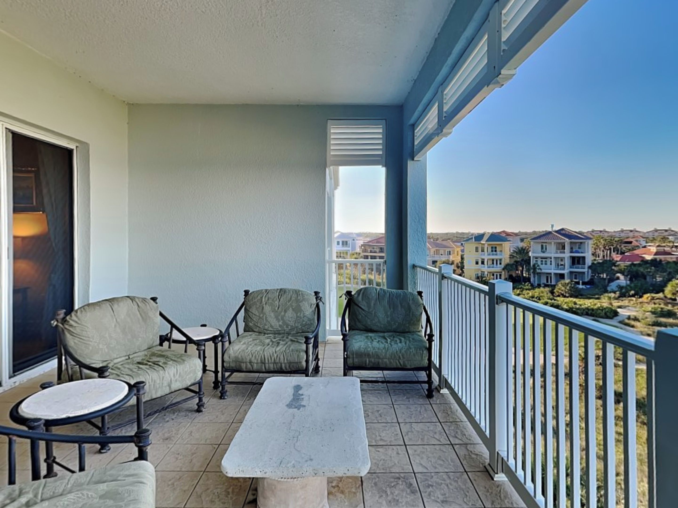 A balcony with two armchairs, a small round table, and a view of a residential area.