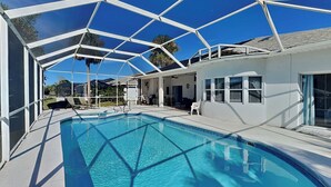 Ein Poolbereich mit Glasveranda, Liegestühlen und Terrasse.
