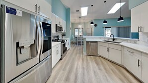A modern kitchen with stainless steel appliances, light wood flooring, and pendant lighting. - Beach Daze by Distinctive Beach Rentals (Palm Coast)