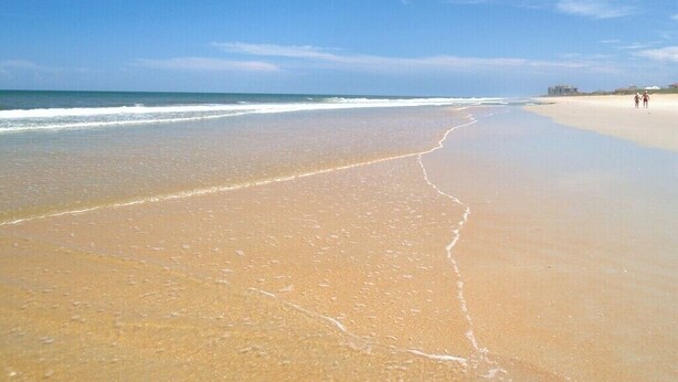 A beach with a clear sky and gentle waves. - Beach Daze by Distinctive Beach Rentals (Palm Coast)