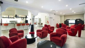 Un área de estar moderna con sillas rojas y una barra.