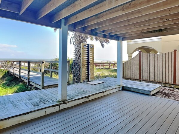 A wooden deck with a pergola overhead, a wooden fence, and a view of the beach.
