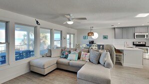 A modern living room with a sectional sofa, a dining area, and a kitchen. - Four Palms by Distinctive Beach Rentals (St. Augustine)