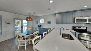 A modern kitchen with white cabinetry, stainless steel appliances, and a central island with seating. - Four Palms by Distinctive Beach Rentals (St. Augustine)