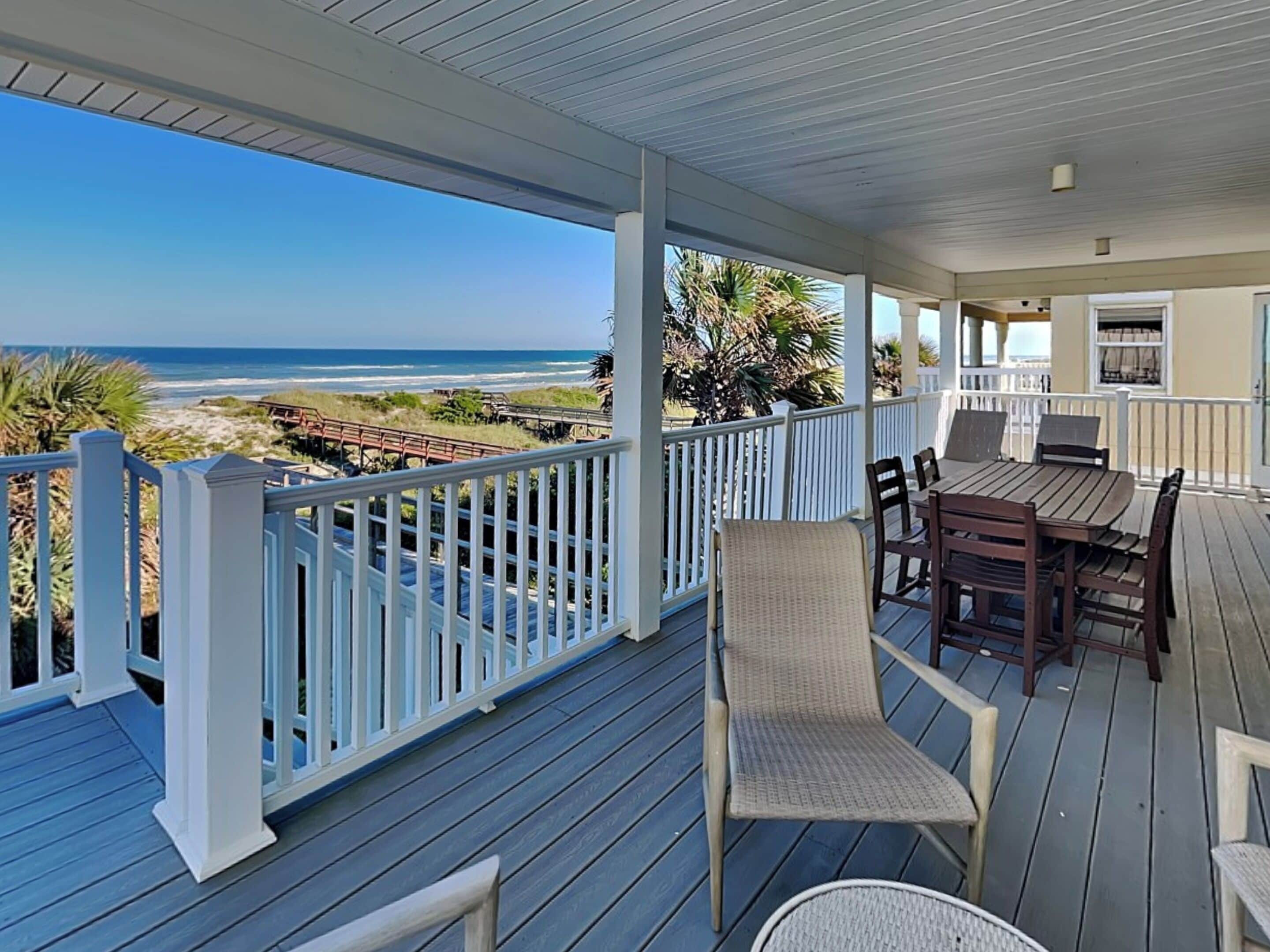 A covered outdoor deck with a view of the beach and ocean.