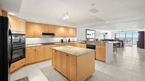 A modern kitchen with wooden cabinets, a black refrigerator, and a central island.