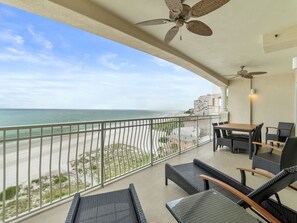 A balcony with a view of the beach and ocean, furnished with wicker chairs and a table. - La Vistana 703 by Distinctive Beach Rentals (Redington Shores)