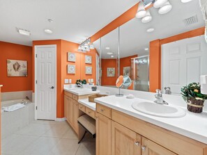 A modern bathroom with two sinks, a large mirror, and a shower. - La Vistana 703 by Distinctive Beach Rentals (Redington Shores)