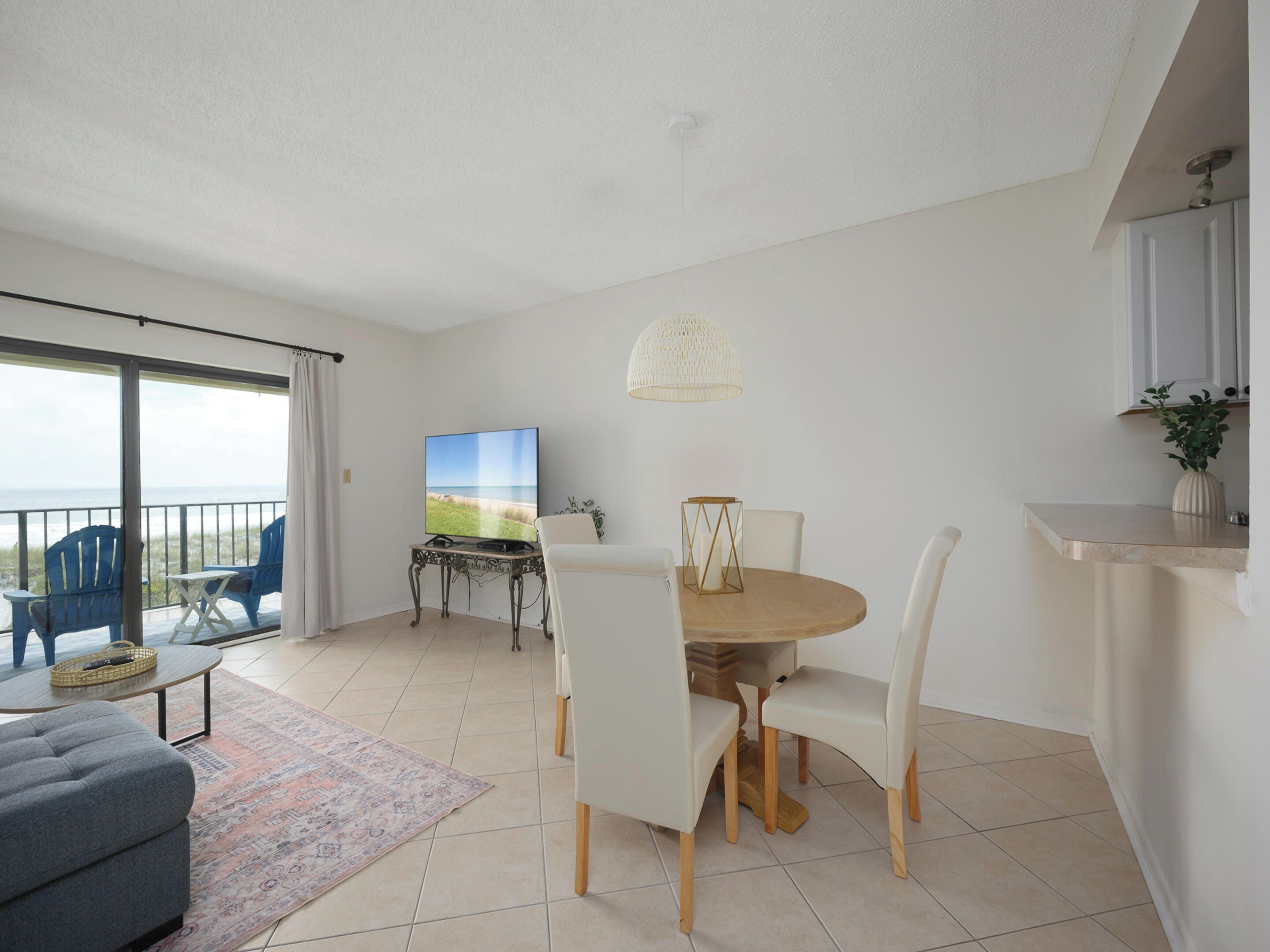 A modern living room with a large TV, a dining table, and a balcony with chairs.