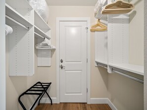 A walk-in closet with white shelving, a door, and a black drying rack.