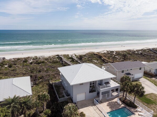 A beachfront property with a large house featuring a balcony, a swimming pool, and a beach view. - Ocean Pearl by Distinctive Beach Rentals (St. Augustine)