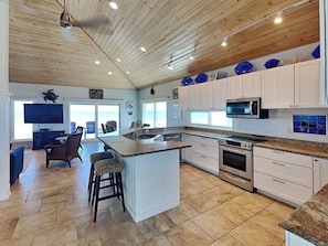 A spacious kitchen with a large island, white cabinetry, and a wooden ceiling. - Ocean Pearl by Distinctive Beach Rentals (St. Augustine)