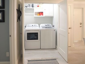 Pesuhuone, jossa on kaksi etukuormitettavaa pesukonetta ja niiden yläpuolella hylly.