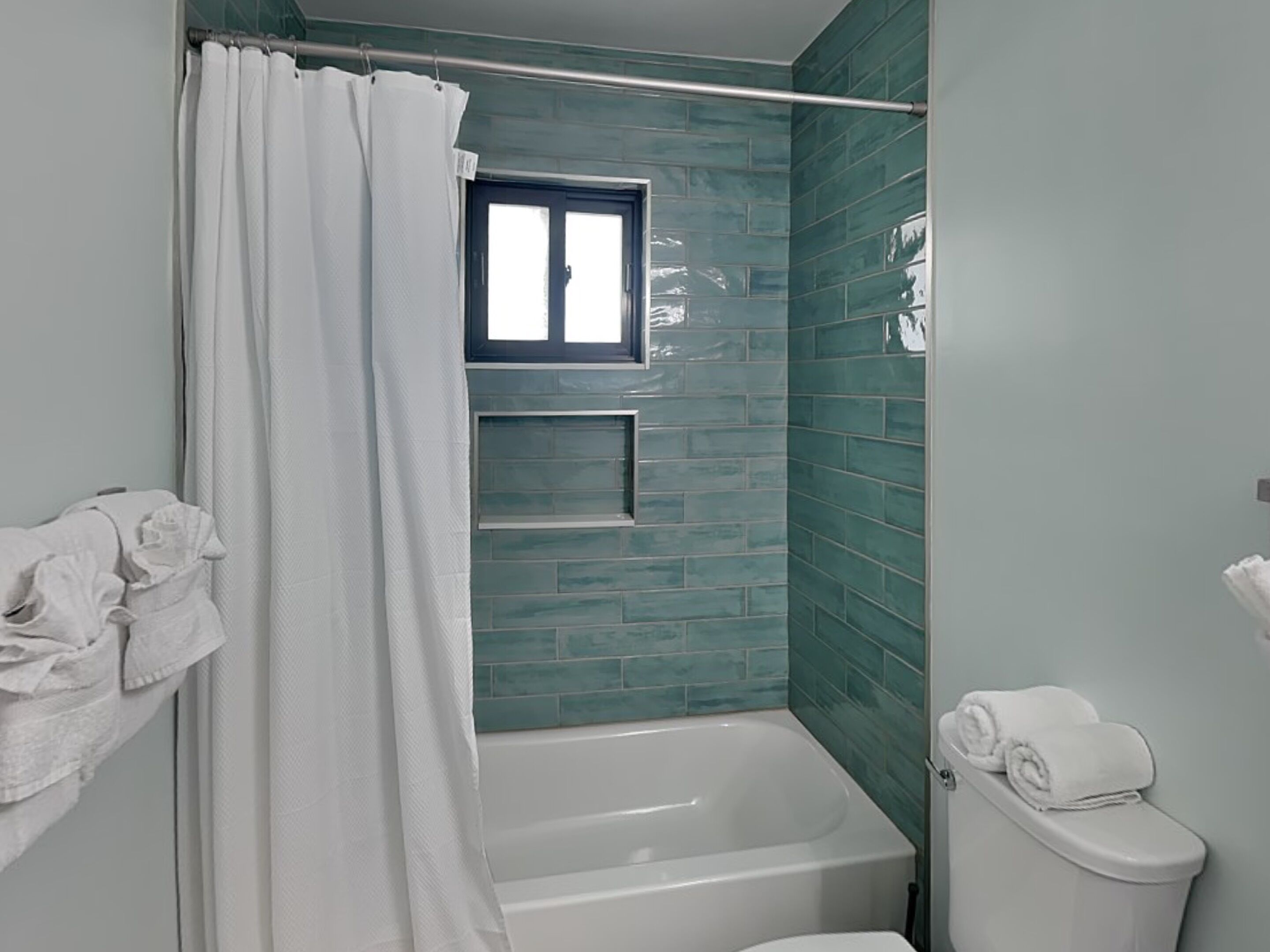 A bathroom with a bathtub, a toilet, and a window.