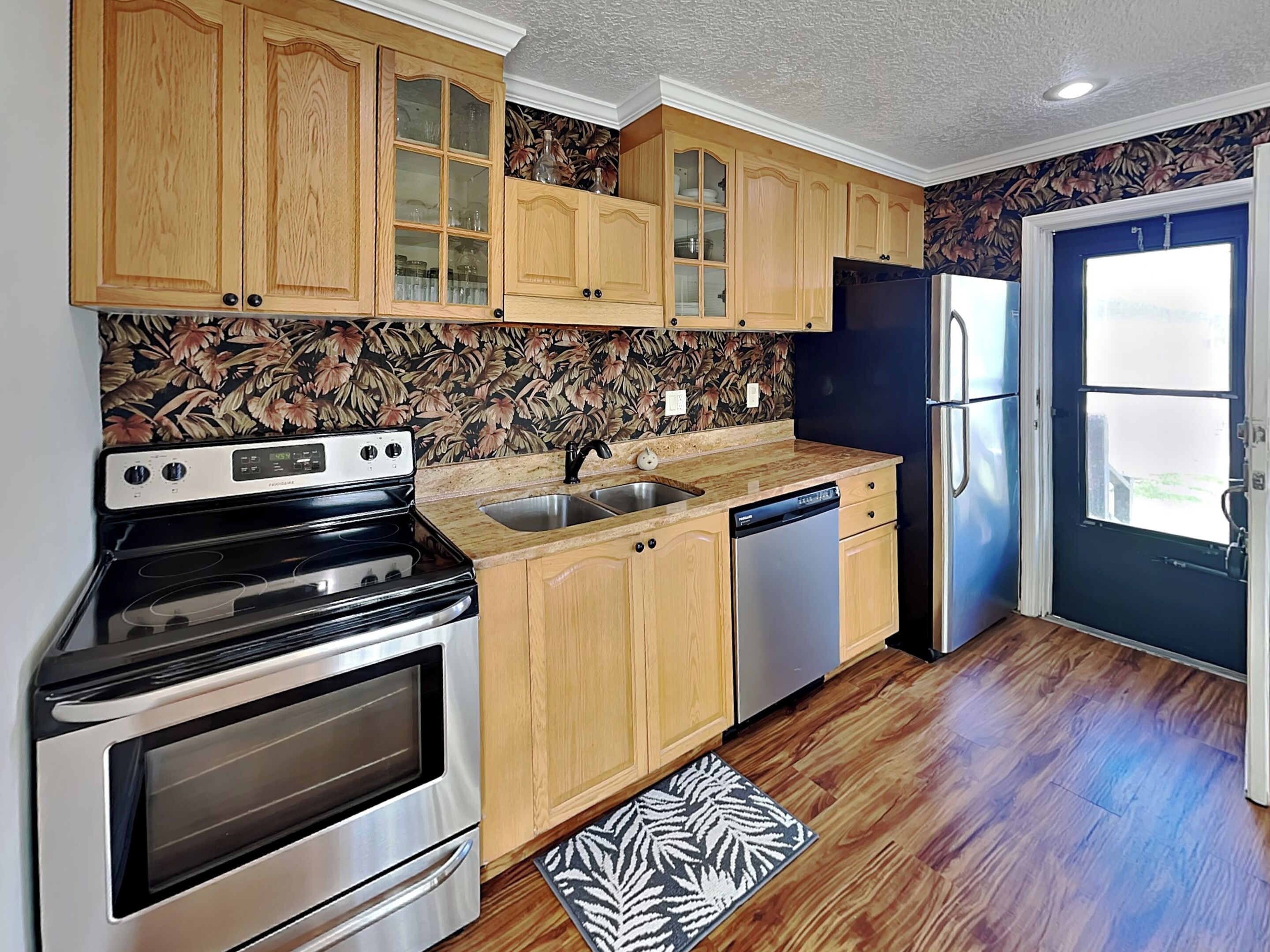 A kitchen with wooden cabinets, a stainless steel oven, a dishwasher, and a refrigerator.