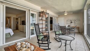 Une vaste terrasse comprenant un coin repas, des fauteuils à bascule et une petite table.