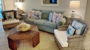 Un salon comprenant un canapé, deux fauteuils, une table basse et une table d’appoint avec une lampe.