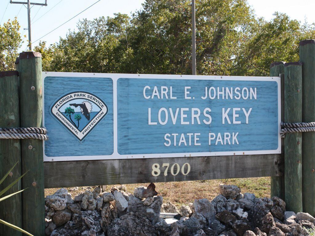 Et træskilt med teksten "Carl E. Johnson Lovers Key State Park 8700" og en logo for Florida Park Service.